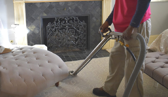 A person is cleaning a rug with equipment