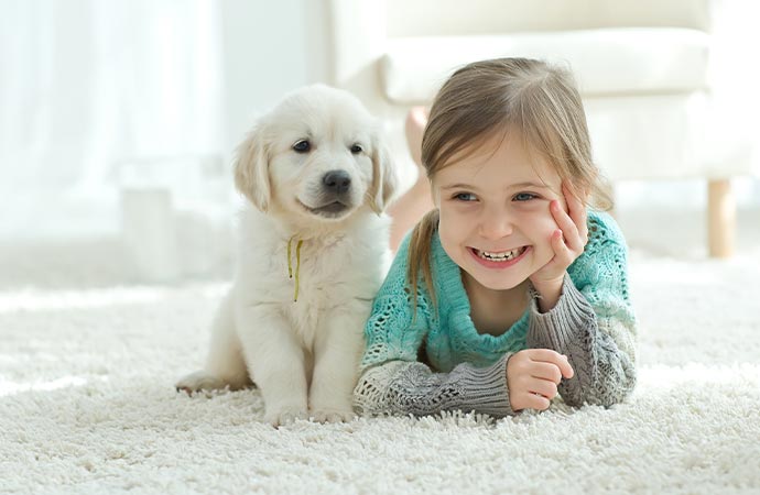 a happy kid and dog on a rug