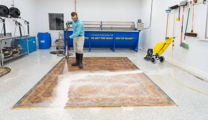 person cleaning rug with a cleaning machine