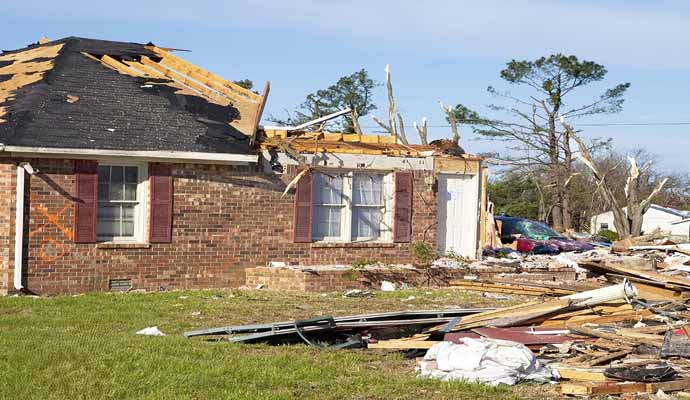 A brick house has severe damage to its roof and structure