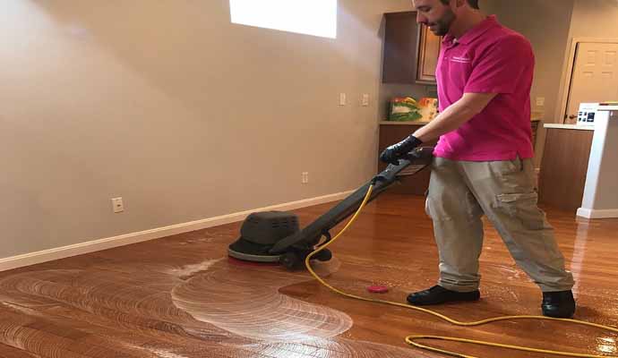 A person is cleaning wooden floor with equipment